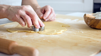 The process of making homemade asterisk shortbread cookies. Male hands cut cookies using a mold made of rolled dough. Authentic home hobby