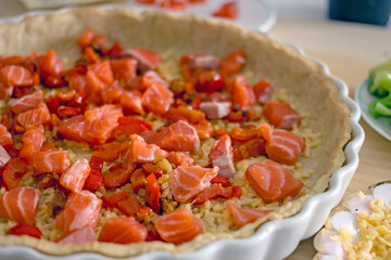 The process of making a quiche fish pie. Shortcrust pastry crust with pieces of red fish in it. Close-up. Fish pie recipe. Salmon pie recipe