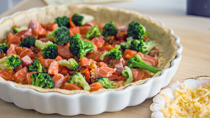 The process of making a quiche fish pie. Shortcrust pastry crust with pieces of red fish in it. Close-up. Fish pie recipe. Salmon pie recipe