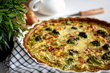 Homemade French quiche pie with salmon and broccoli in a baking dish close-up