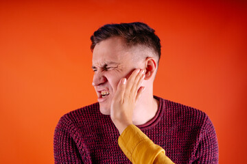 Man getting slapped on orange background. Unhappy scared man getting slapped standing on orange...