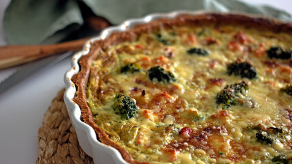 Homemade French quiche pie with salmon and broccoli in a baking dish close-up
