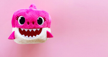 adorable pink baby shark soft toy on pink background. Sweet childhood. Free copy space. Top view