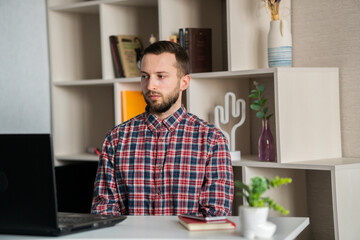 Fototapeta premium Focused young businessman wear headphones study online watching webinar podcast on laptop listening learning education course conference calling make notes sit at work desk, elearning concept