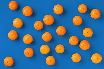 Fruit pattern of fresh orange tangerine or mandarin on blue background. Flat lay, top view. Pop art design, creative summer concept. Citrus in minimal style.