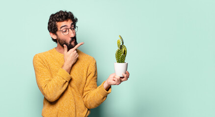 young crazy bearded man holding a cactus house plant