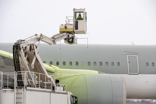 Winter at the airport. Snow storm. Airplane de-icing before take off. De-icing the aircraft before the flight. The de-icing machine sprinkles the wing of a passenger plane with de-icing fluid.