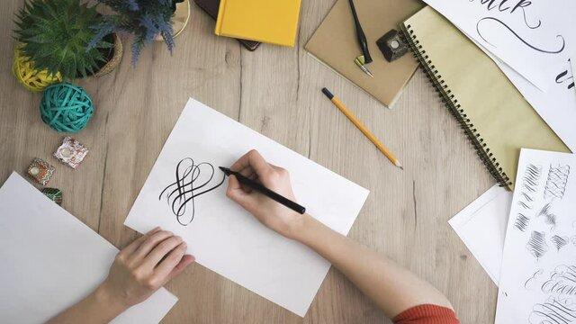Female Hand is Writing Calligraphic Twirl View from Above