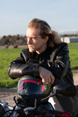 Fototapeta na wymiar Caucasian white man leaning on a black motorcycle biker helmet with sane jacket