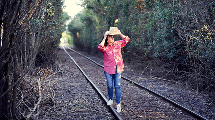 Beautiful Young Woman Standing By Train Tracks Young woman walking on the railway tracks.