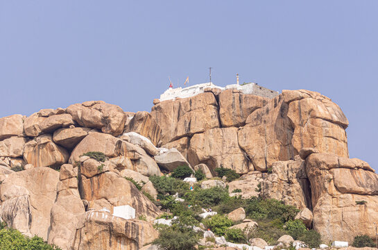 Hunumanahalli, Karnataka, India - November 9, 2013: Kishkinda, Anjanadri Hill, Anjaneya Parvat, the birthplace of Hanuman God now a white temple on top of beige boulder hill under blue sky.