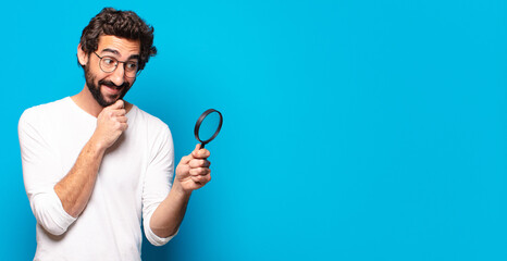 young crazy bearded man looking and trying to find with a magnifying glass