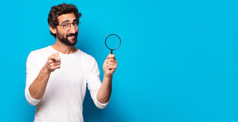 young crazy bearded man looking and trying to find with a magnifying glass