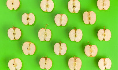Fruit pattern on green background. Apple halves geometrical layout. Flat lay, top view. Food background. .  Pop art design, creative summer concept.