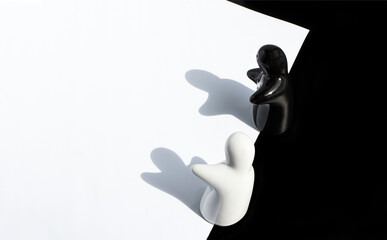 Black and white ceramic figurines on a black and white background. Management or leadership. The concept of racial equality, equal opportunity