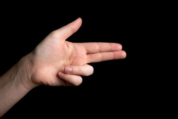 Person Holding symbolic gun with hand gesture, playing killing shooting weapons isolated on dark...
