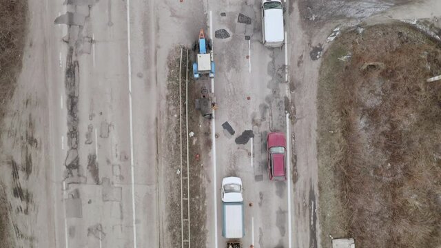 Road workers manually fill the pits and potholes on the road surface. Workers repair highway surface - aerial drone Overhead Shot