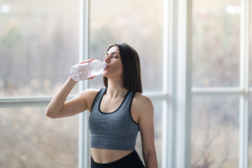 Beautiful Turkish sportwoman is drinking water after the workout session.