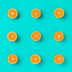Fruit pattern of fresh mandarin slices on blue background. Flat lay, top view. Pop art design, creative summer concept. Half of citrus in minimal style. Tangerine.
