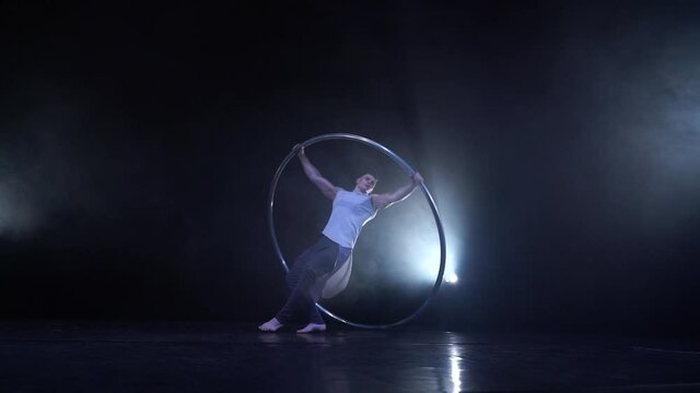 Muscular Circus artist spinning on a Cyr wheel in slow motion. Concept of movement, motion and balance