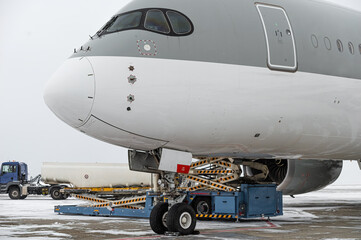 Front landing gear of big passenger aircraft closeup. Modern passenger aircraft at winter airport apron. Nose of modern passenger aircraft.
