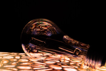 Green energy concept lightbulb with coffee beans reflection. Dark background