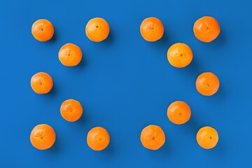 Fruit pattern of fresh orange tangerine or mandarin on blue background. Flat lay, top view. Pop art design, creative summer concept. Citrus in minimal style.