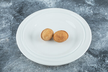 A white plate of sweet walnut shaped cookies