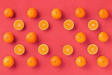 Fruit pattern of fresh orange tangerine or mandarin on living coral background. Flat lay, top view. Pop art design, creative summer concept. Citrus in minimal style.