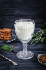 Vintage cut glass of milk, chocolate cookies and flowers on a dark background