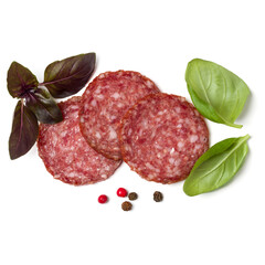 Slices of salami isolated on white background closeup. Sausage and basil leaves top view.