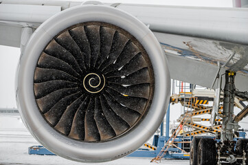 Aircraft Jet Engine turbine. Modern passenger airplane parked at the winter airport apron before departure, the view on the wing, the chassis rack gear, and engine.