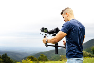 Young muscular Caucasian man manning a camera on top of a gimbal while working recording a scene in...