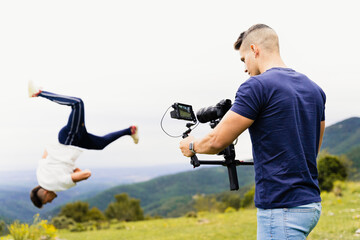 Young and fit cameraman recording with a gimbal a person doing sports, specifically stunts...