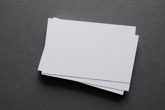 Mock up a stack of blank white cards &uuml;n a grey table, space for text or a template