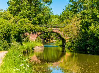 A bridge and reflection on the Grand Union Canal in Market Harborough in summertime