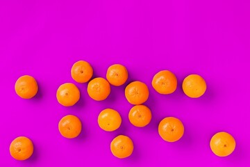Fruit pattern of fresh orange tangerine or mandarin on lilac background. Flat lay, top view. Pop art design, creative summer concept. Citrus in minimal style.