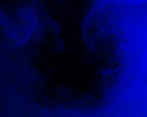 Abstract background of chaotically mixing puffs of blue smoke on a dark background