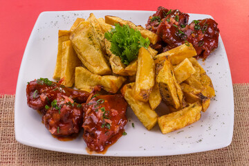 Comida gastronómica de pollo y papas nativas fritas en plato para restaurante, alitas a la barbacoa