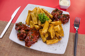 Comida gastronómica de pollo y papas nativas fritas en plato para restaurante, alitas a la barbacoa