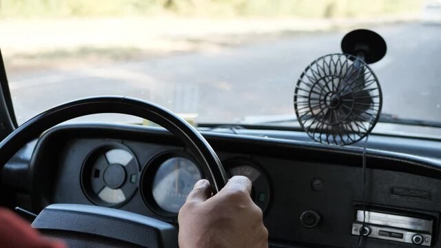male hands on the steering wheel of an old, vintage, retro car. View of the road through the windshield of the car. slow motion.