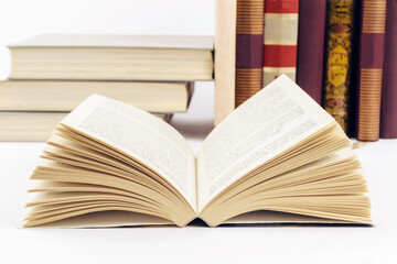 Open book with stack of books in background. Selective focus.