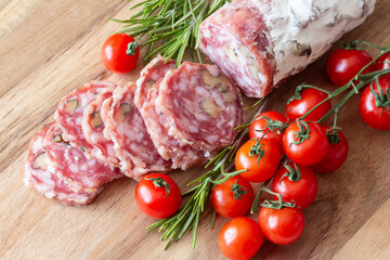 Sliced Air-dried salami with rosemary and cherry tomatoes - wood background