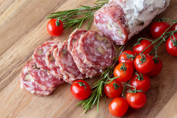 Sliced Air-dried salami with rosemary and cherry tomatoes - wood background