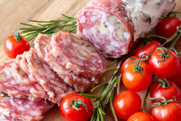 Sliced Air-dried salami with rosemary and cherry tomatoes - wood background