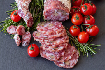 Sliced Air-dried salami with rosemary and cherry tomatoes - grey stone background
