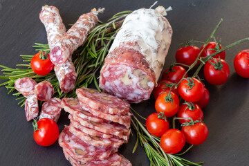 Sliced Air-dried salami with rosemary and cherry tomatoes - grey stone background