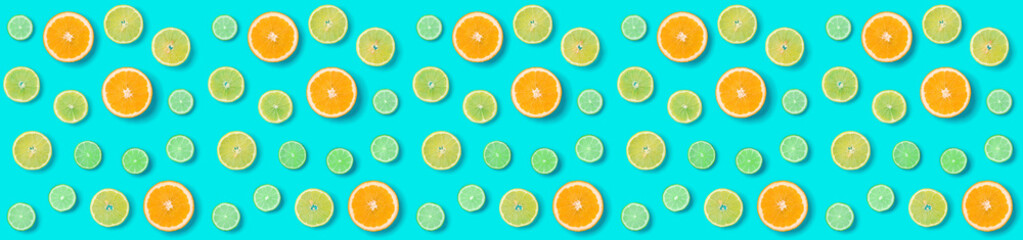 Fototapeta premium Creative layout made of colorful tropical fruits isolated on blue background. Minimal summer exotic concept. Citrus fruit seamless patternOrange, Lime, Lemon slices background.