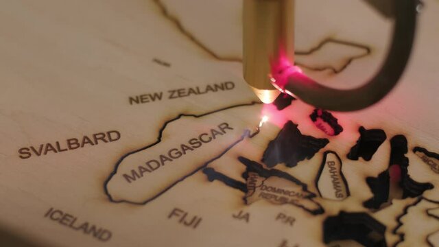 Cnc laser cutting machine cuts world map on wooden plank and plywood
