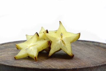 Fototapeta premium Star shaped slices of carambola fruit on a wooden background. Carambola fruit with slice of star fruit.